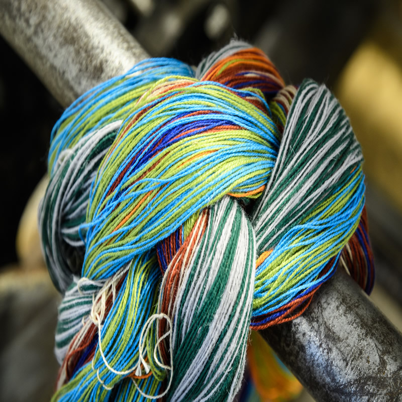 multicoloured strands of wool wrapped round a metal bar